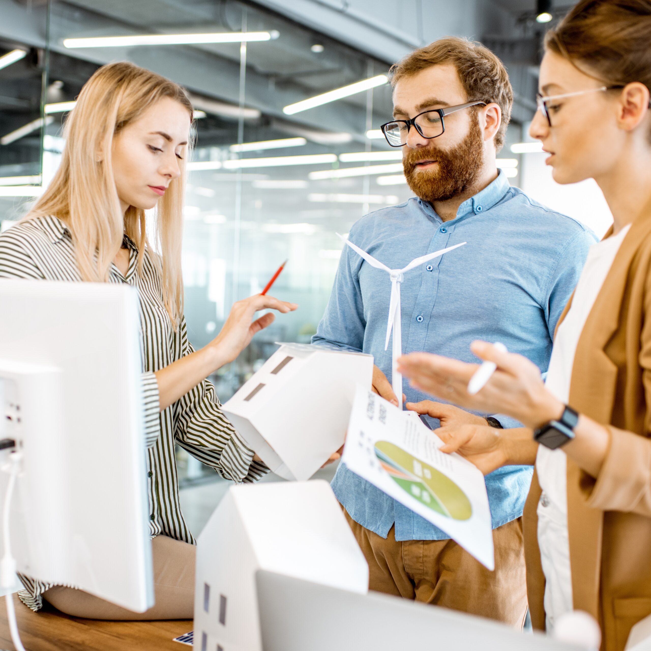 Junge Menschen in Business Outfit stehen zusammen und besprechen Fragen zu AURELO Energiepark Manager, dem ERP für Erneuerbare von Allgeier inovar.