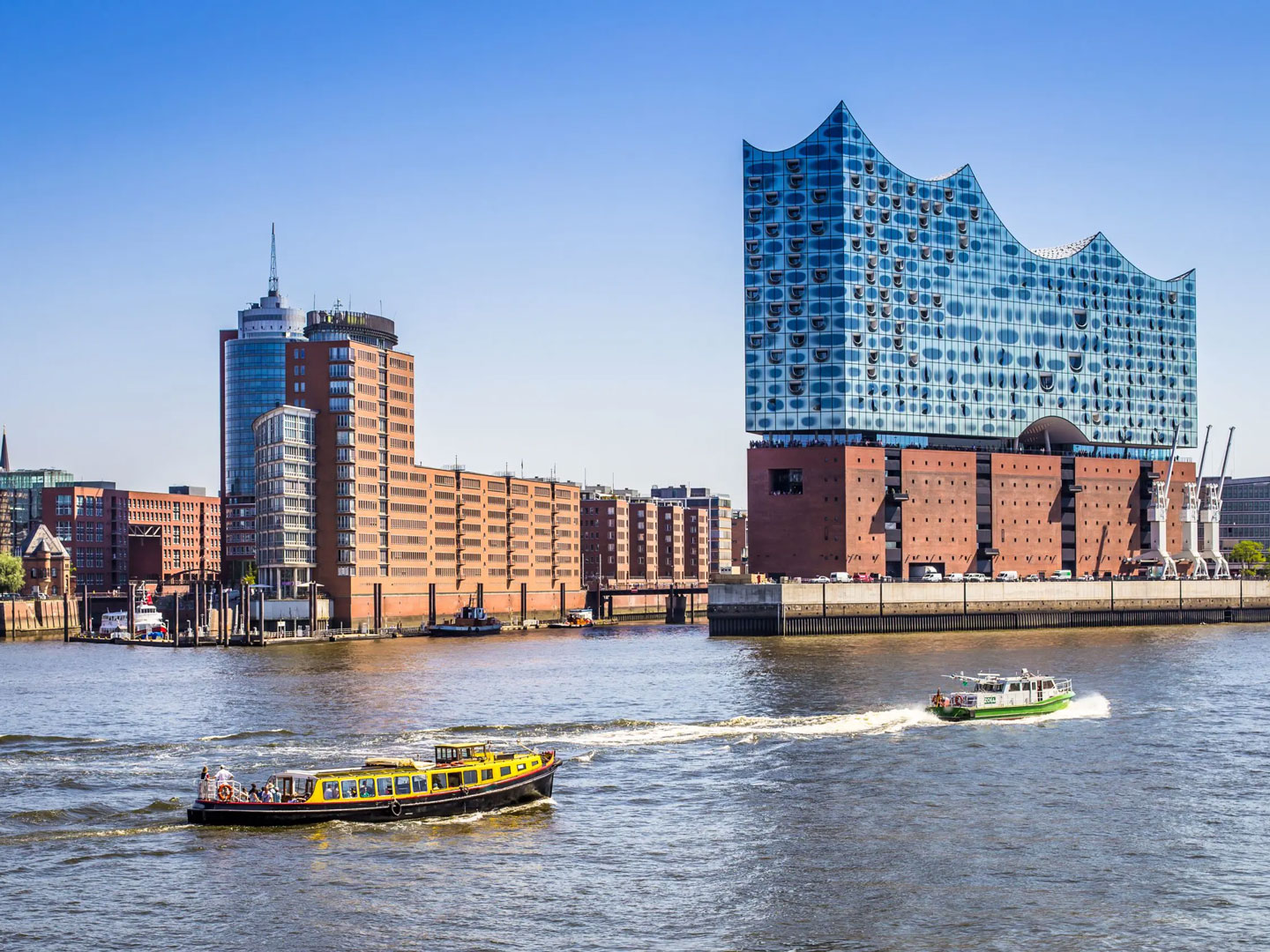 Allgeier inovar mit Standort in Hamburg, erkennbar an der Elbphilharmonie und der Alster mit Booten und vor blauem Himmel