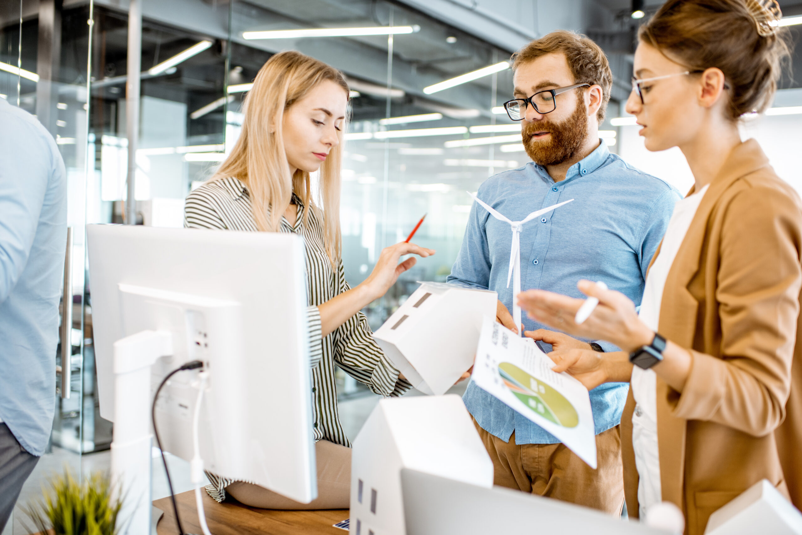 Junge Menschen in Business Outfit stehen zusammen und besprechen Fragen zu AURELO Energiepark Manager, dem ERP für Erneuerbare von Allgeier inovar.