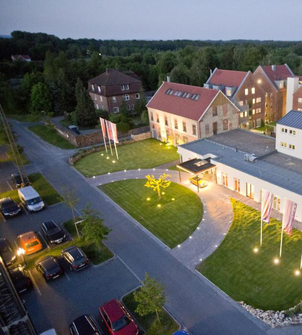 Hell erleuchteter Haus-Wohnblock vor dem Autos stehen.