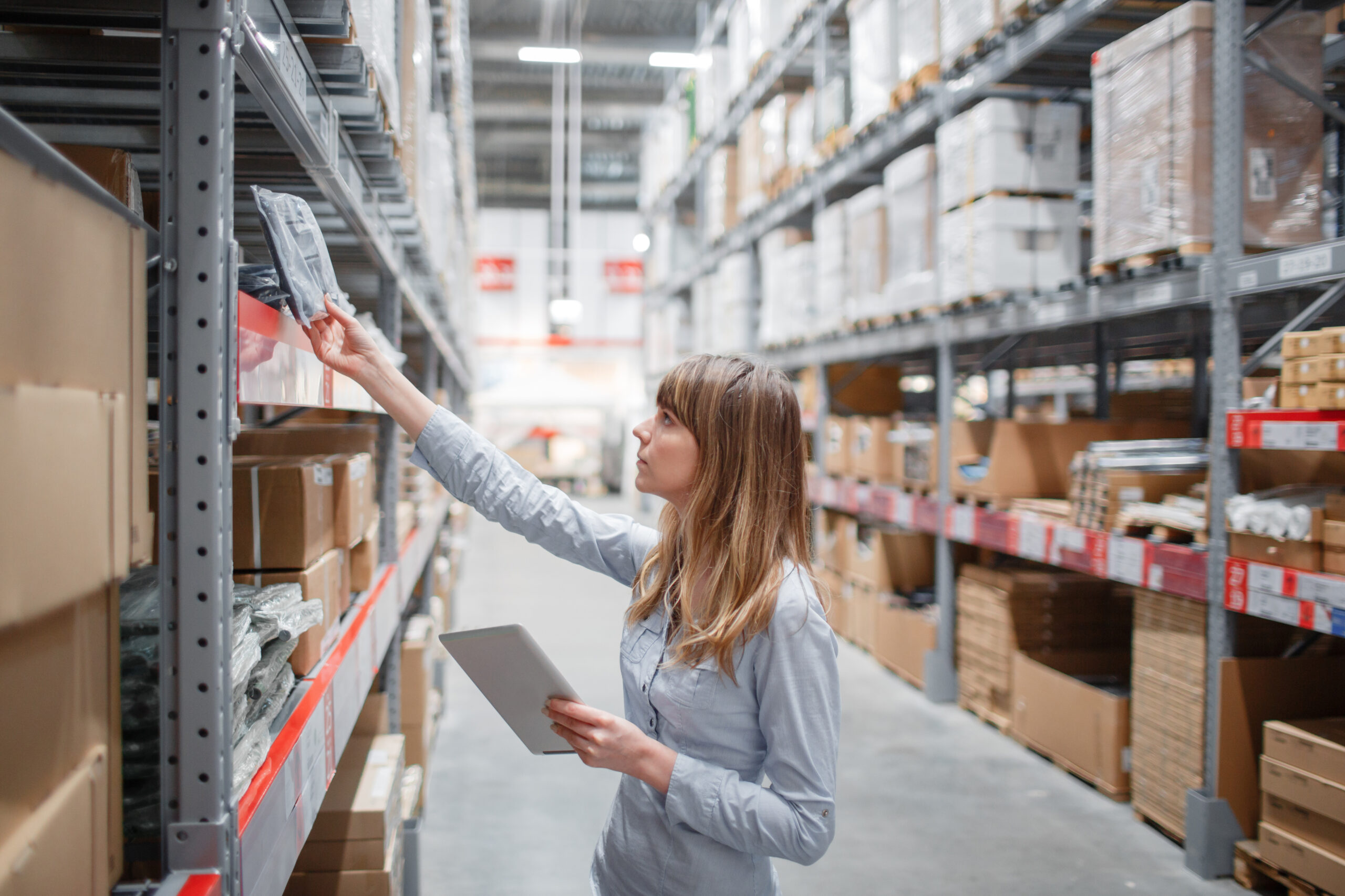 Serious staff woman wrting on notepad at supermarket