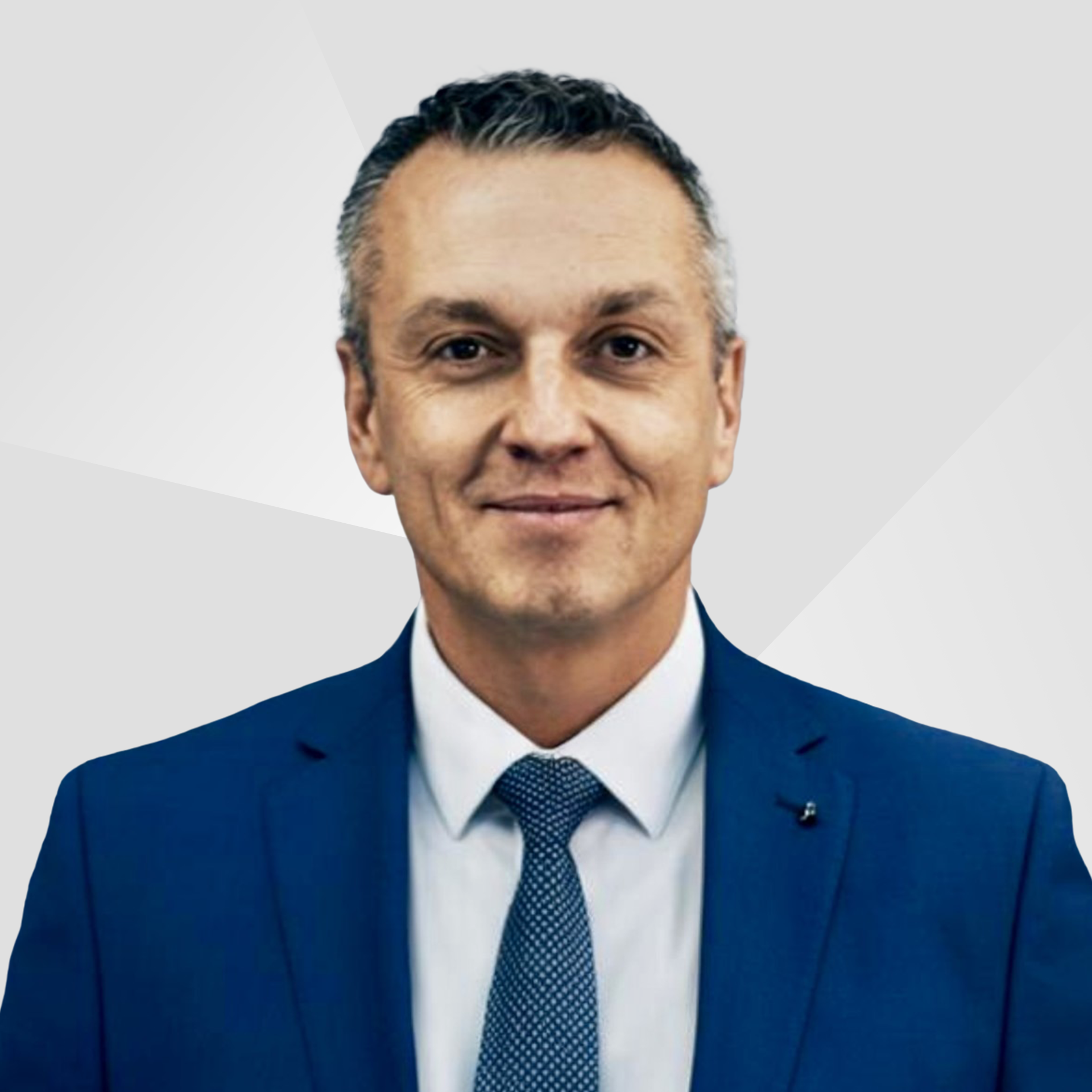 Ralph Kelle, Head of Sales E-Commerce bei Allgeier inovar, weißes Hemd, dunkelblaue Krawatte und Anzug vor grauem Hintergrund.