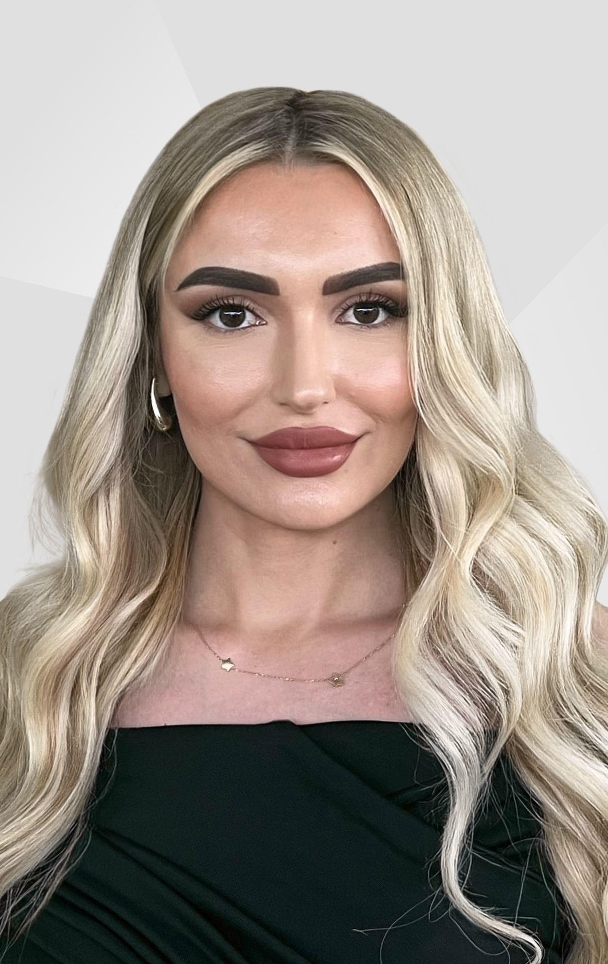 Habibe Hyusein, Referentin Recruiting bei Allgeier inovar, schwarzes Kleid vor einem grauen Hintergrund.