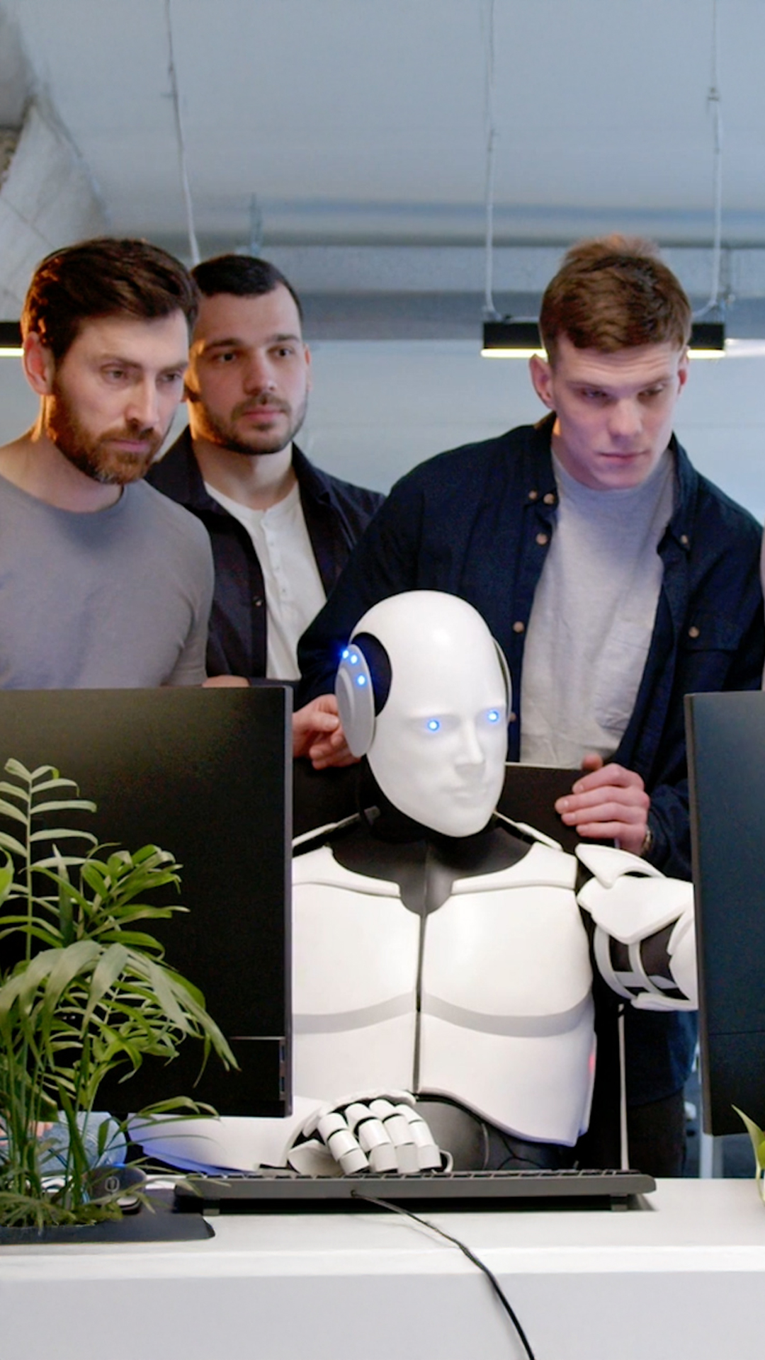 Sieben Personen stehen in einem Büroraum hinter einem Schreibtisch, an dem eine AI sitzt und die Arbeit für sie macht. Das soll die Lösung Microsoft Copilot Studio visualisieren.