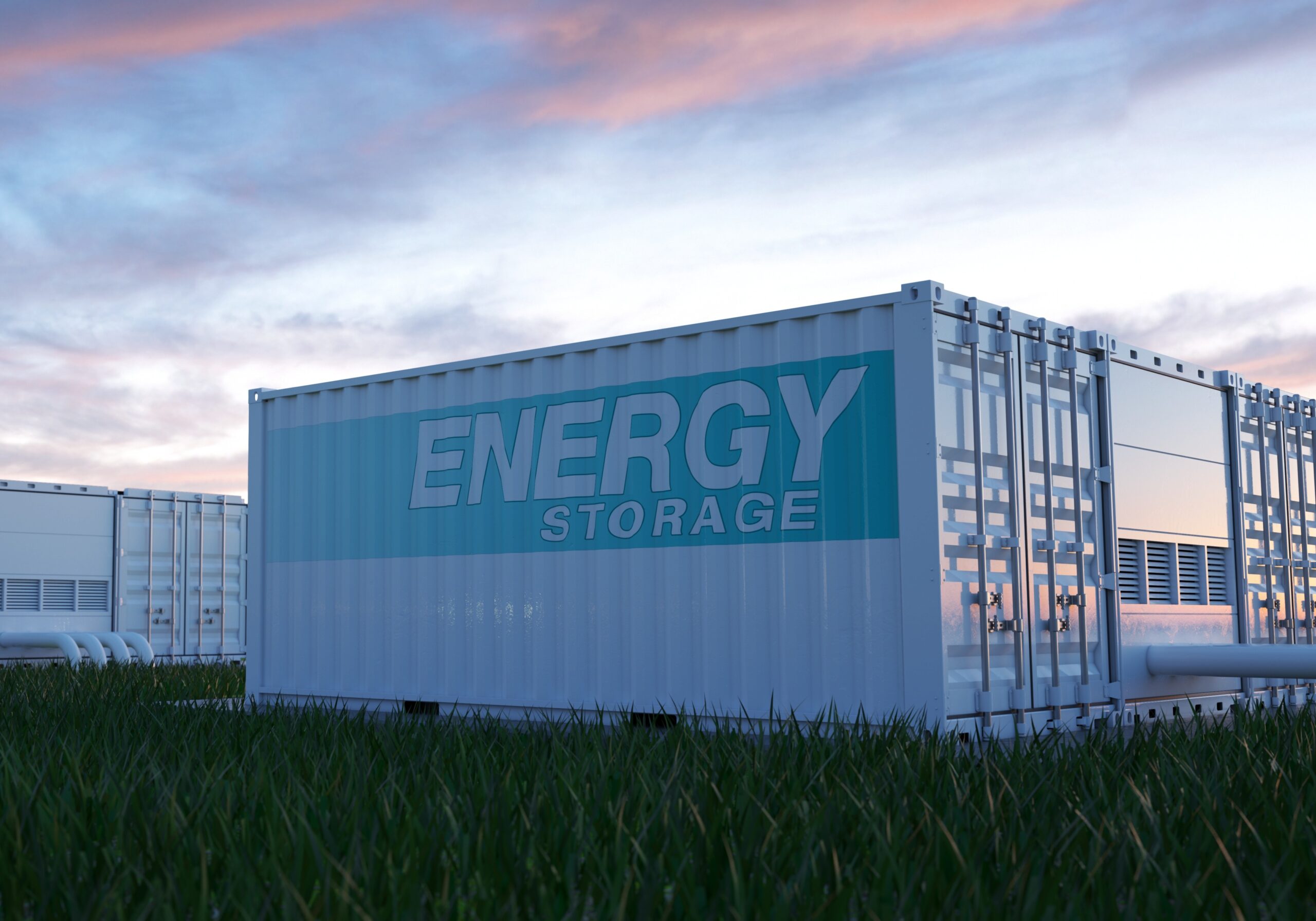 Batteriespeicher zum Speichern von Erneuerbaren Energien aus Wind- und Solarparks stehen auf einer Wiese.