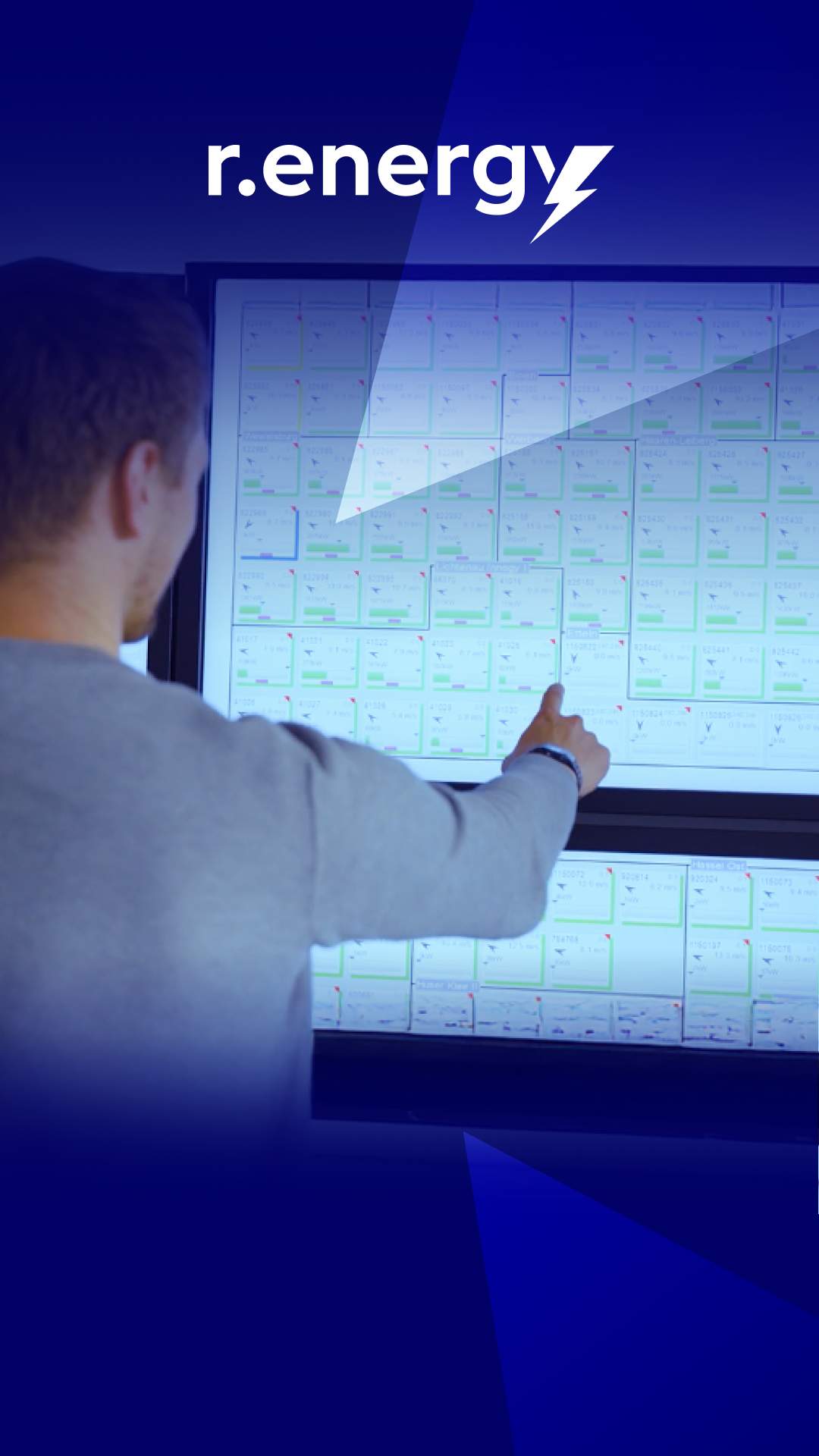 Junger Mann steht vor einem großen Bildschirm, er bedient ihn per touch und steuert die Prozesse in der Erneuerbaren digital.